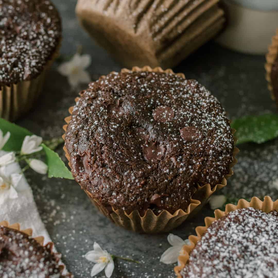 a flatlay style photo of green smoothie chocolate muffins topped with chocolate chips 