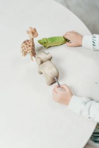 child holding wooden animal toys enjoying poetry for young children.