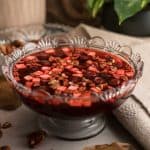 a decorative crystal bowl with black cherry jello salad topped with cream cheese and pecans
