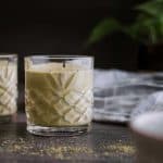 a glass of matcha protein shake on table with a dark background