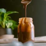 close up shot of a spoon lifting tahini balsamic dressing out of the jar