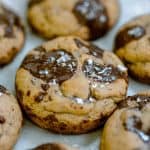 Close up of a barley chocolate chip cookie with finishing salt on top on a table of the cookies.