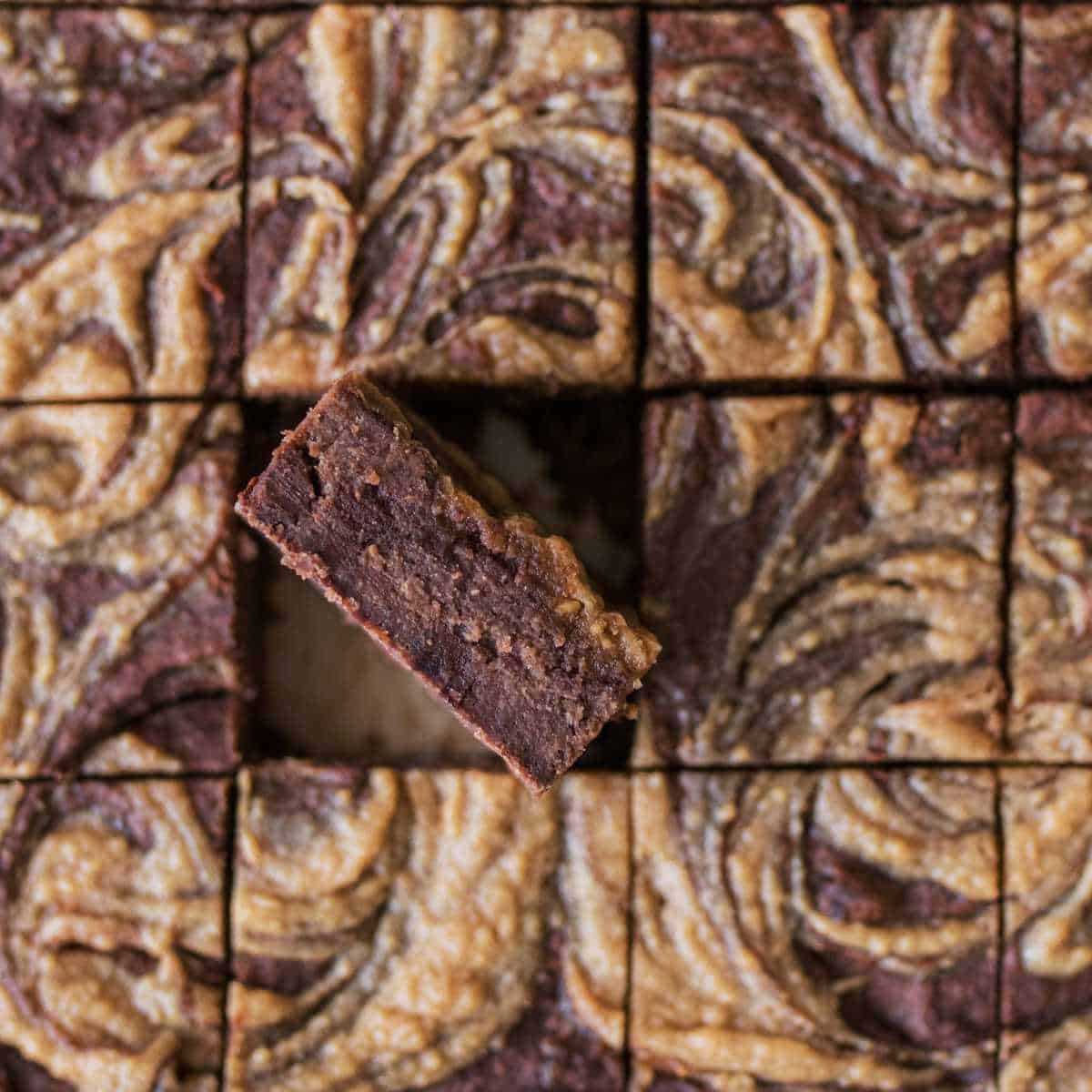 Single square, black bean brownie standing up in a pan of brownies laying flat.