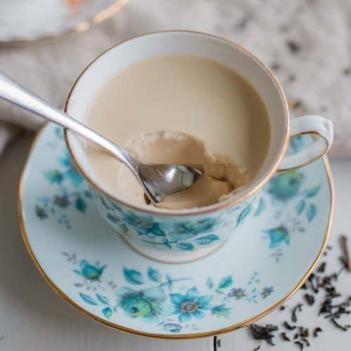 A spoon sitting inside a scooped out bit of Earl Grey Panna Cotta inside an ornate tea cup.