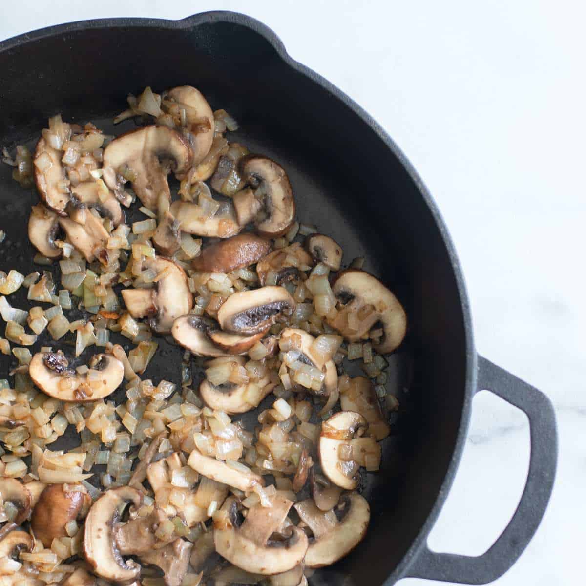 Cut onion and mushroom frying in an a cast iron skillet.