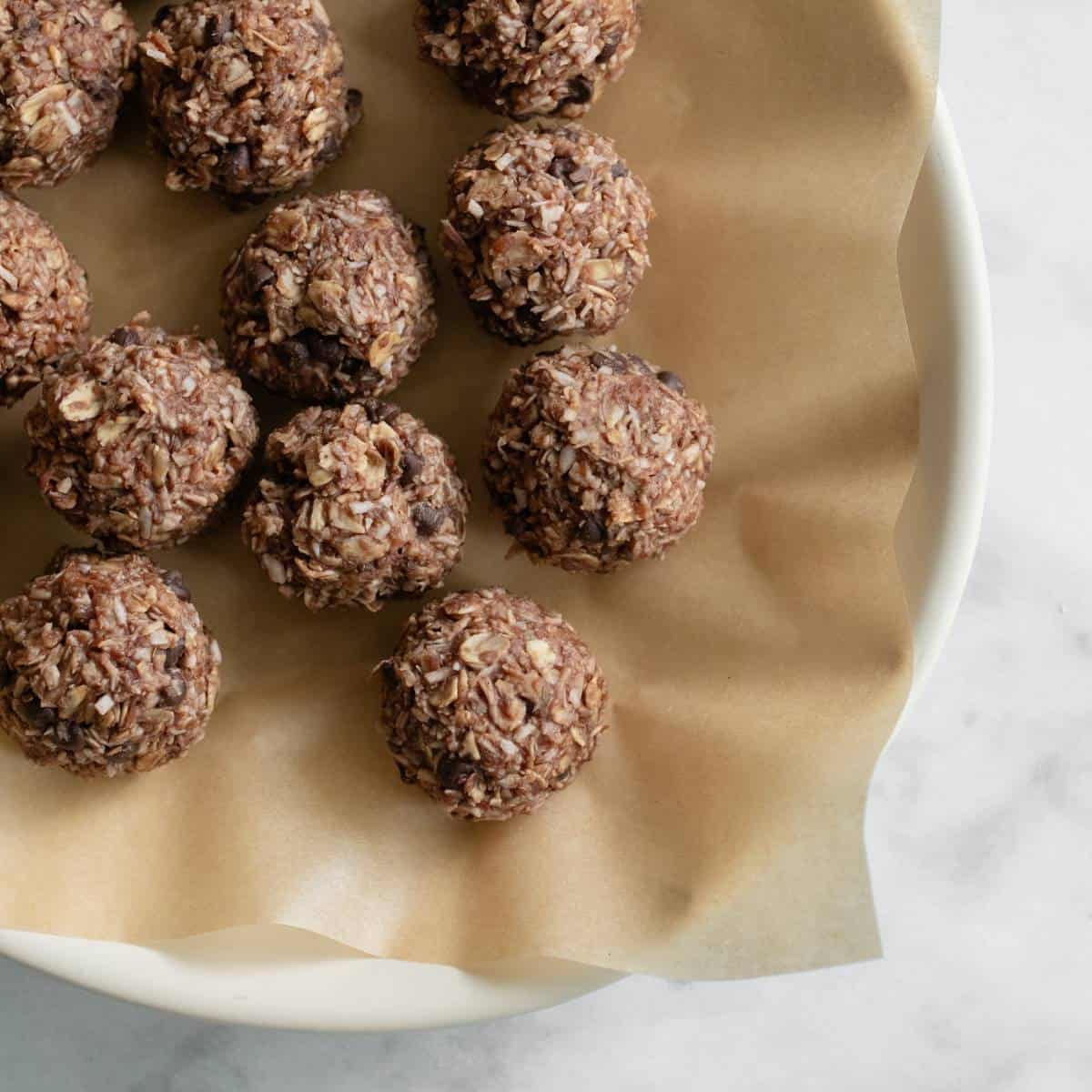 Chilled energy balls served on a parchment paper lined plate.