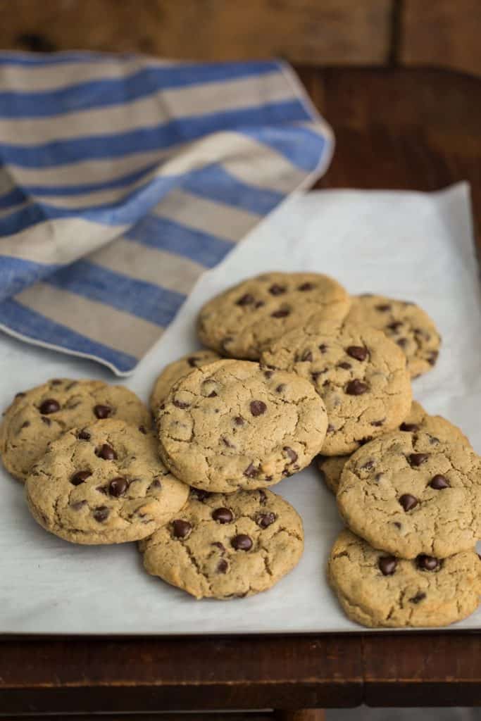 Eleven barley chocolate chip cookies on parchment paper on a staged table.