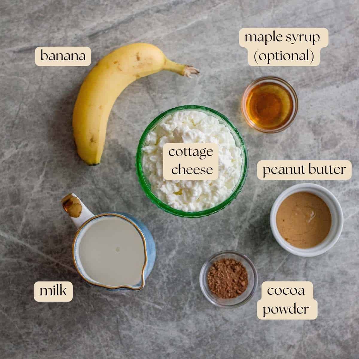 Ingredients to make cottage cheese ice cream in bowls, pinch bowls and resting on a marble countertop.