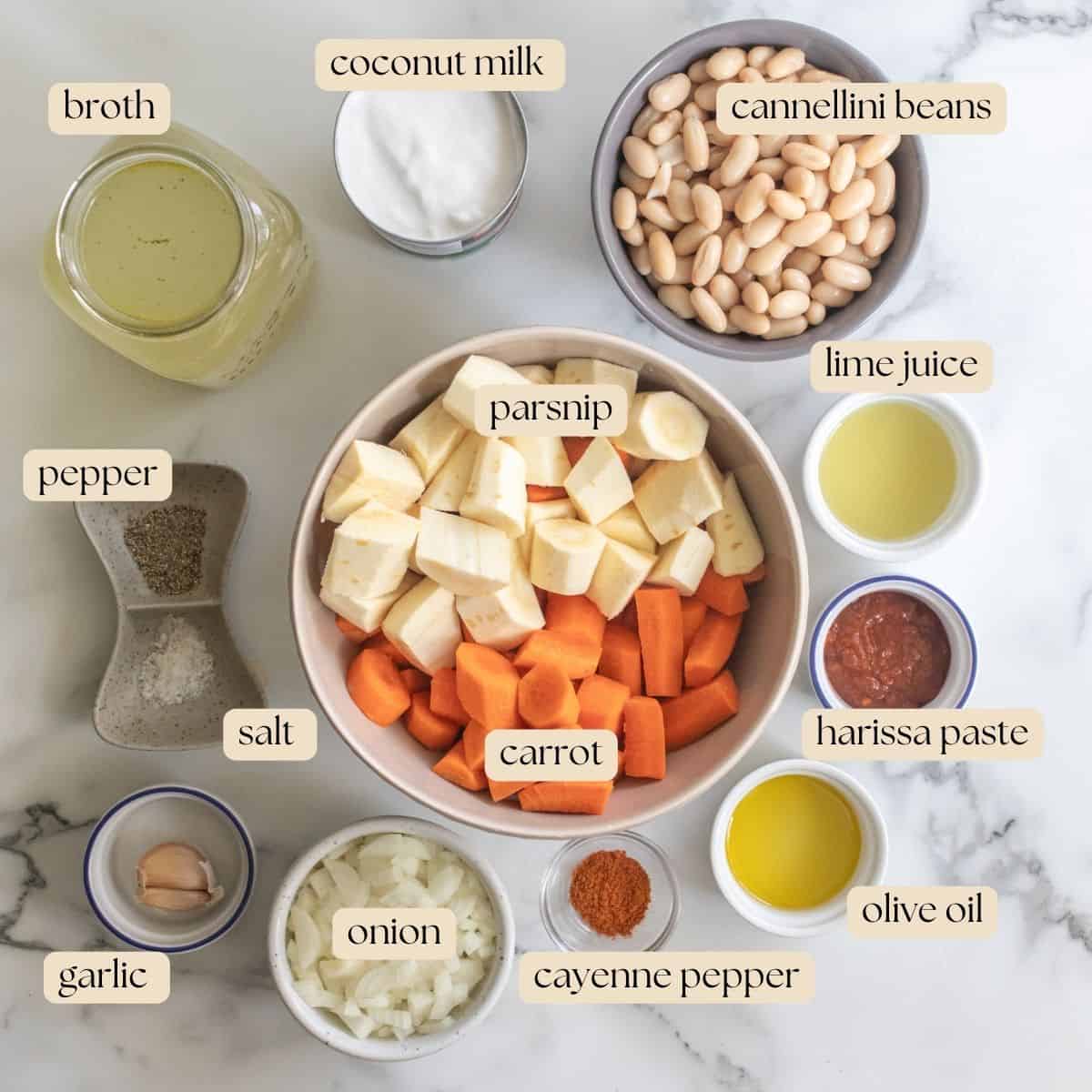 Ingredients to make cream carrot and parsnip soup in bowls on a countertop.