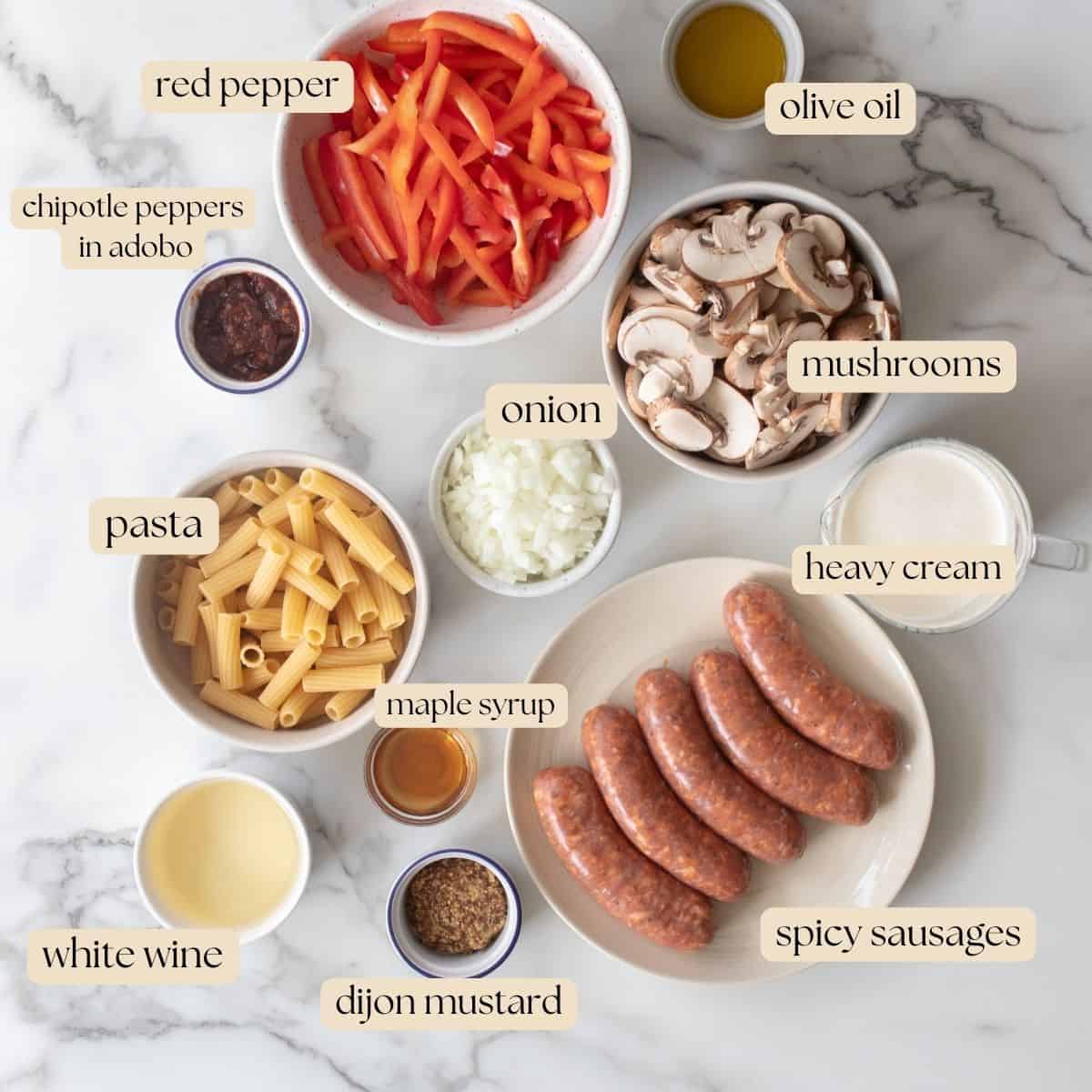 Ingredients to make spicy sausage pasta in bowls, plates and cups on a countertop.