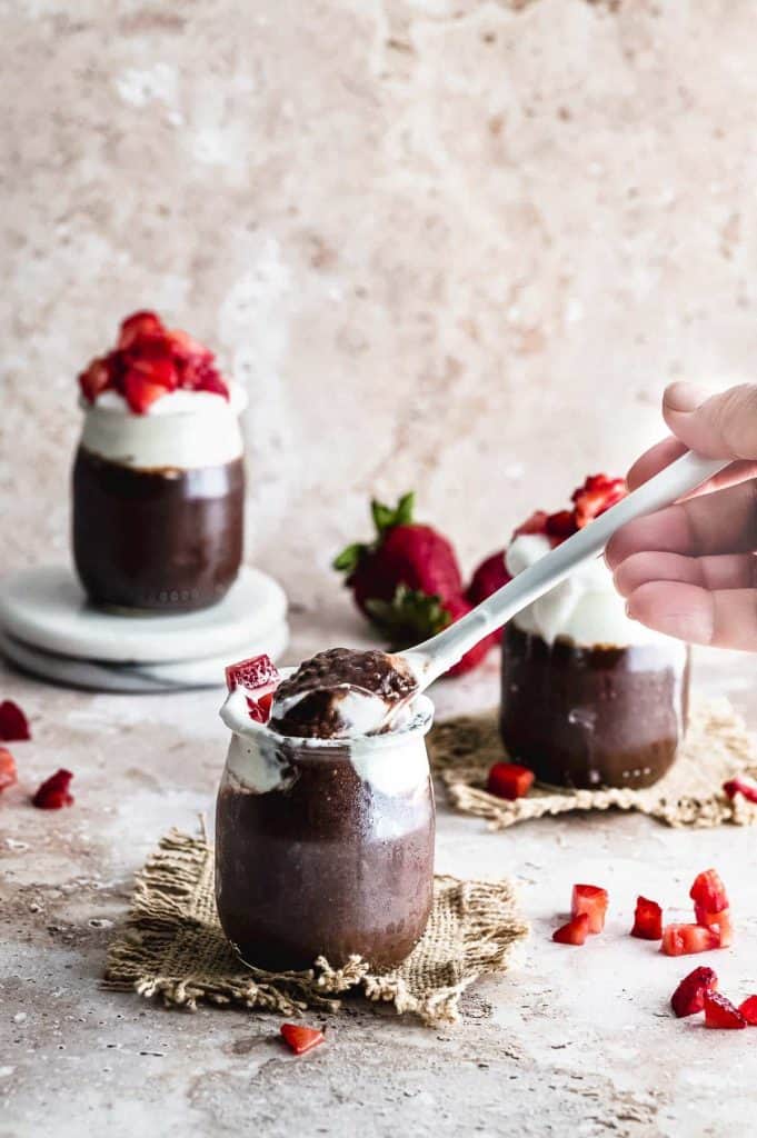 Chocolate pudding with cream on top in vintage, miniature glass milk jars.