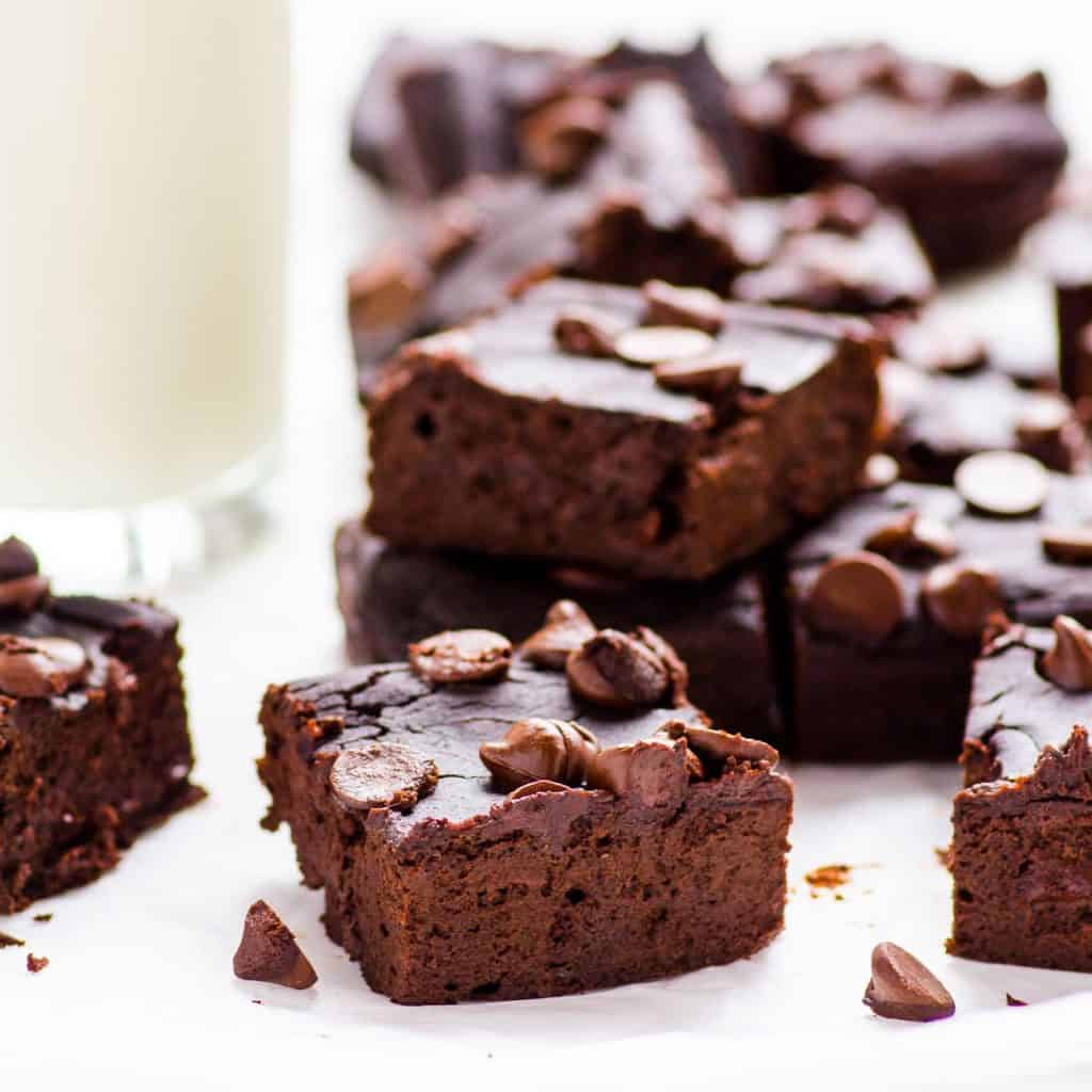 Group of black bean brownies on a white table with one stacked on top.