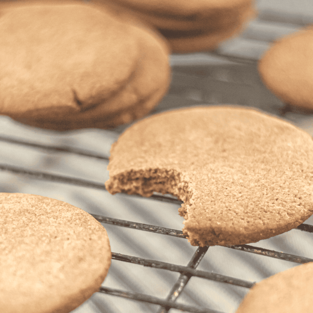 Barley cinnamon cookies on a cooling rack with one in focus, with a bite taken out of it.