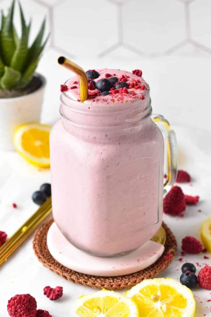 Cottage cheese smoothie in a mason jar with raspberry crumbs and whole blueberries on top.