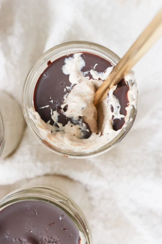 Blended overnight oats with chocolate cover broken by a golden spoon in a mason jar.