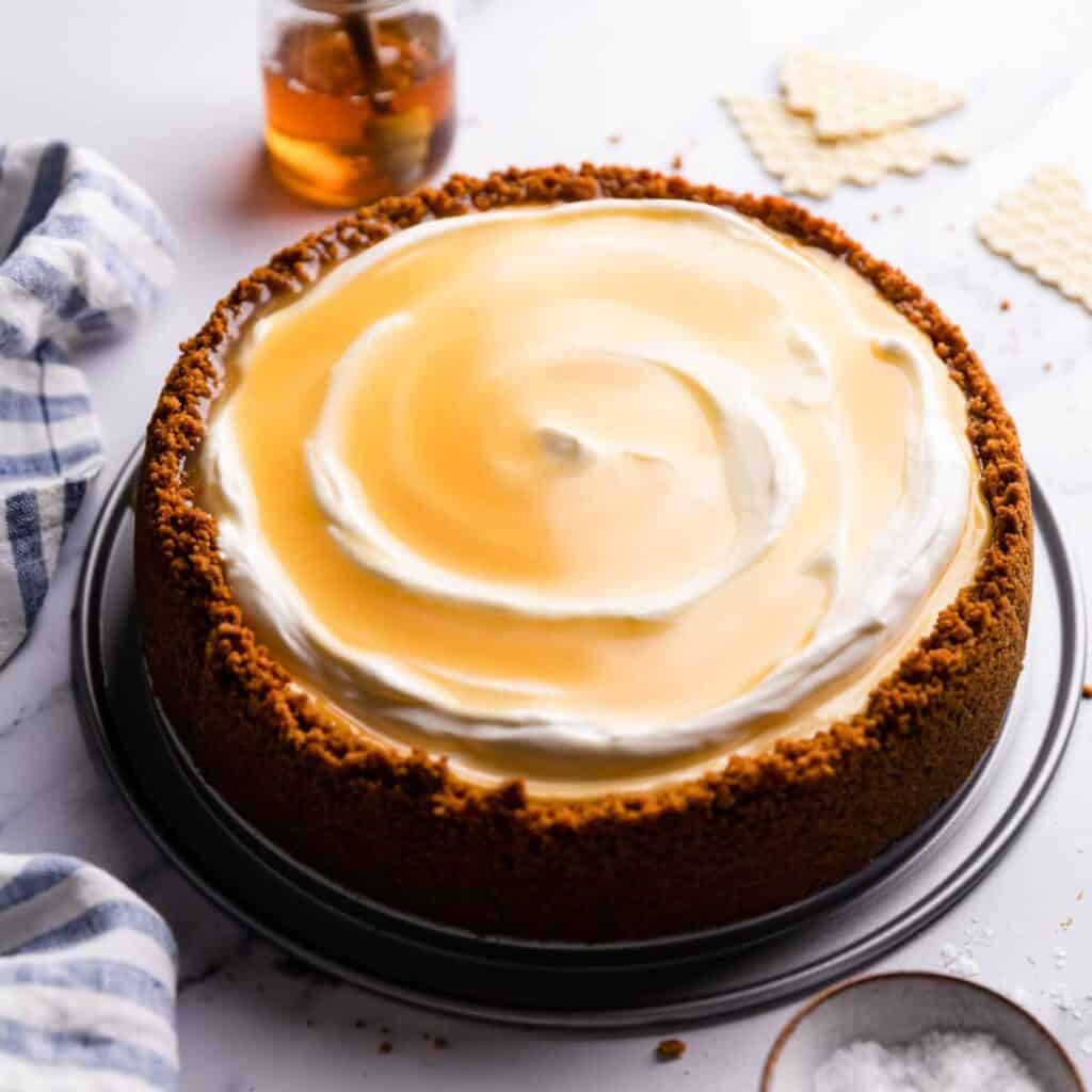 Honey cheesecake on a staged countertop with a jar of honey.