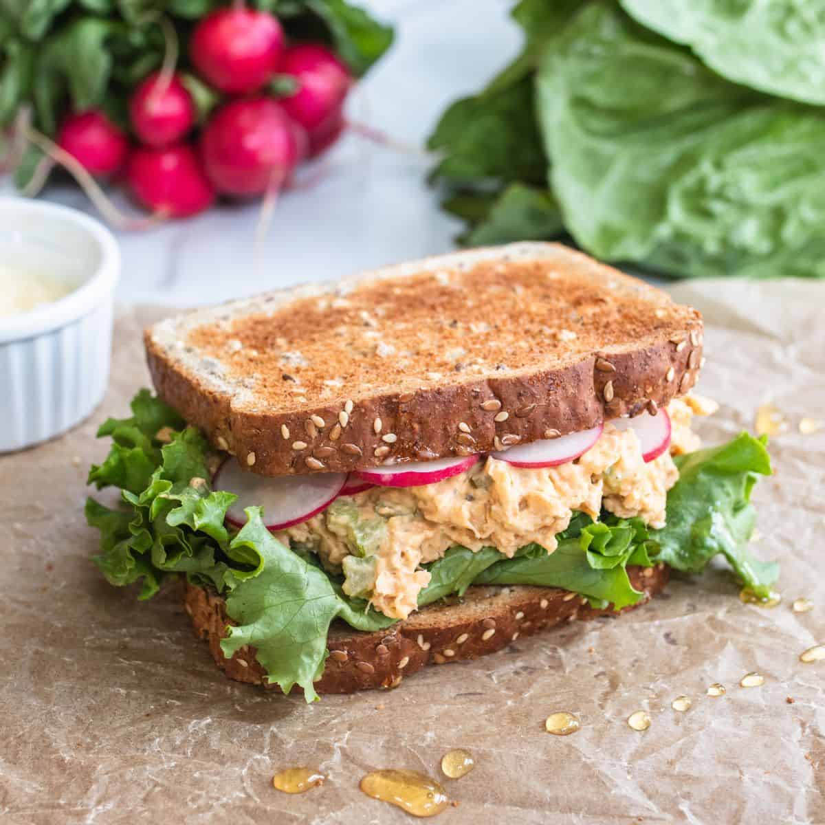 Chickpea smash sandwich with radishes and lettuce leaves showing.