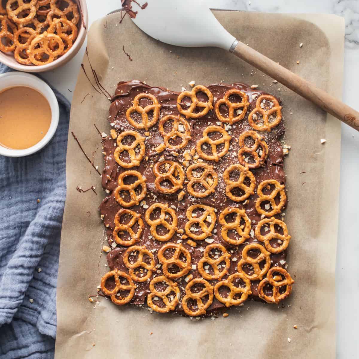 Crushed and whole pretzels spread over melted chocolate making date bark.