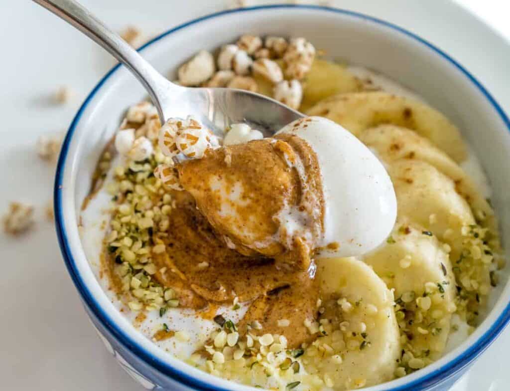 Whipped cottage cheese in a bowl with hemp hearts, puffed quinoa, almond butter and bananas.
