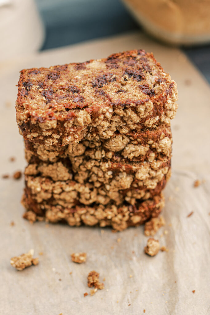 Five pieces of streusel banana bread stacked on top of each other on parchment paper.