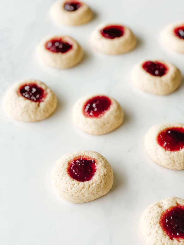 Strawberry filled thumbprint cookies on a white countertop.