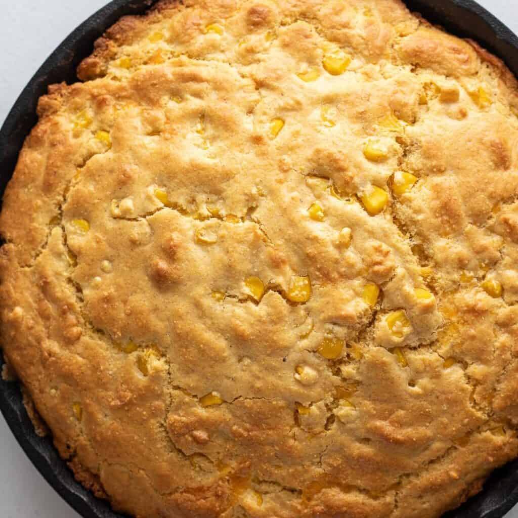 Close up of cornbread showing corn kernels in a cast iron pan.