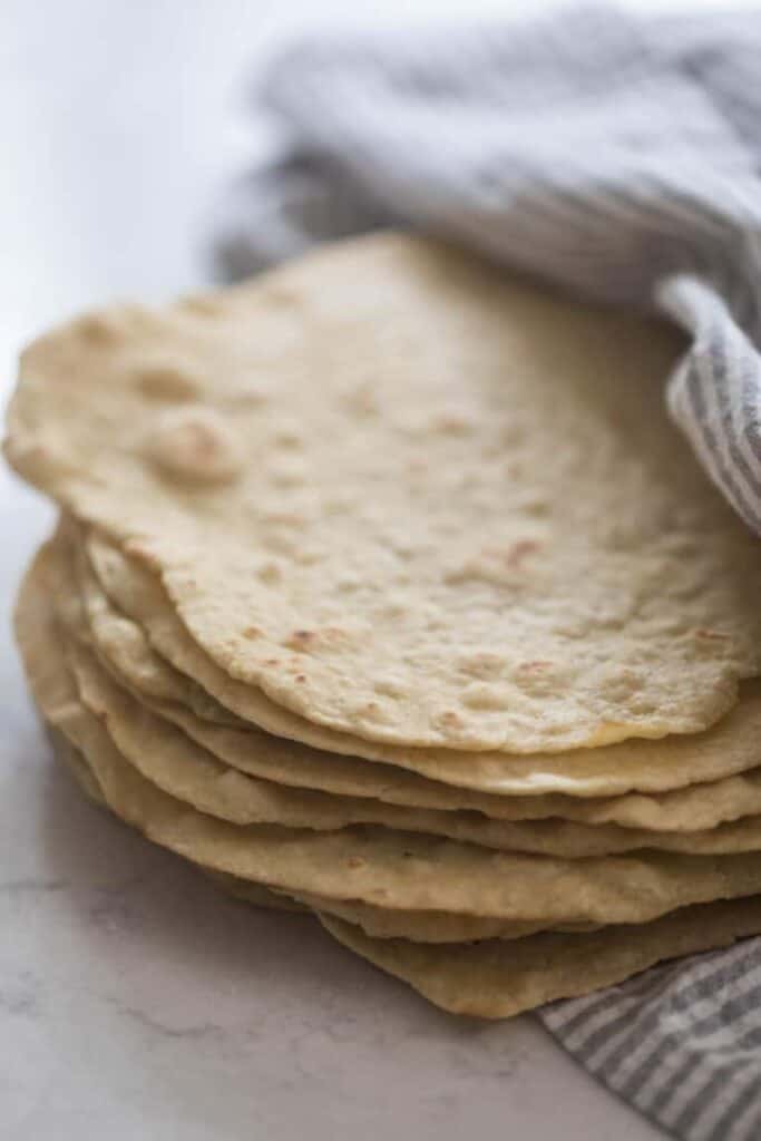 8 Einkorn tortillas in a towel on a marble countertop.