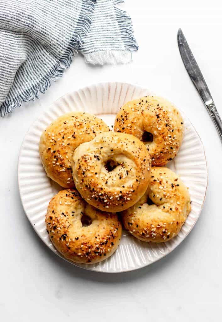 5 Multi-grain bagels with cream cheese on a plate.