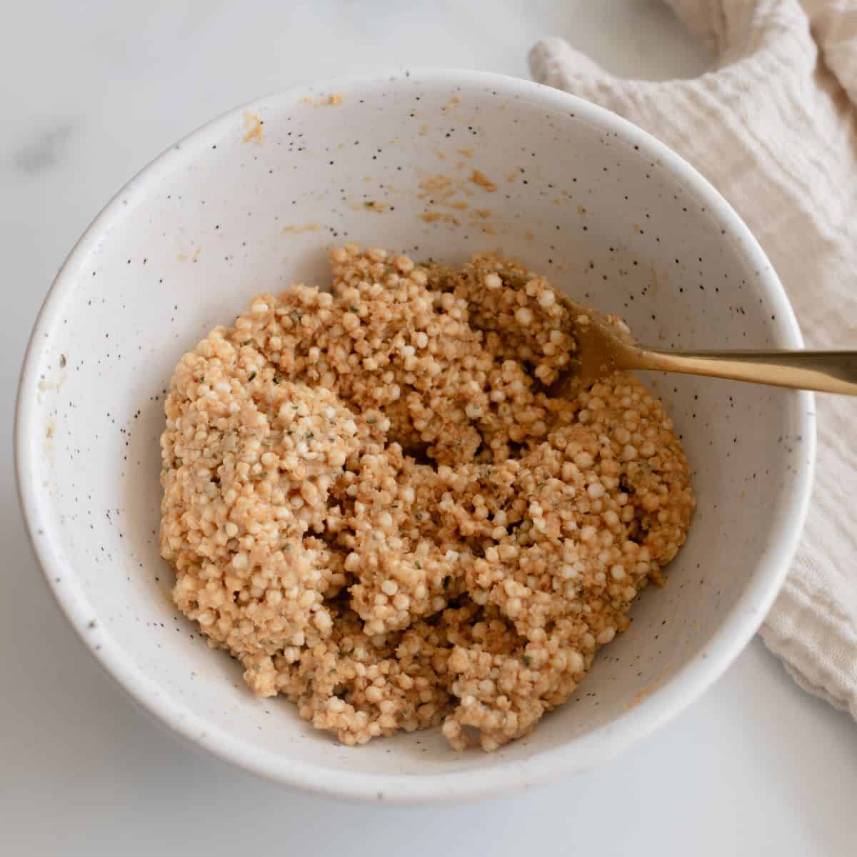 All ingredients mixed together for quinoa bites in a ceramic mixing bowl.